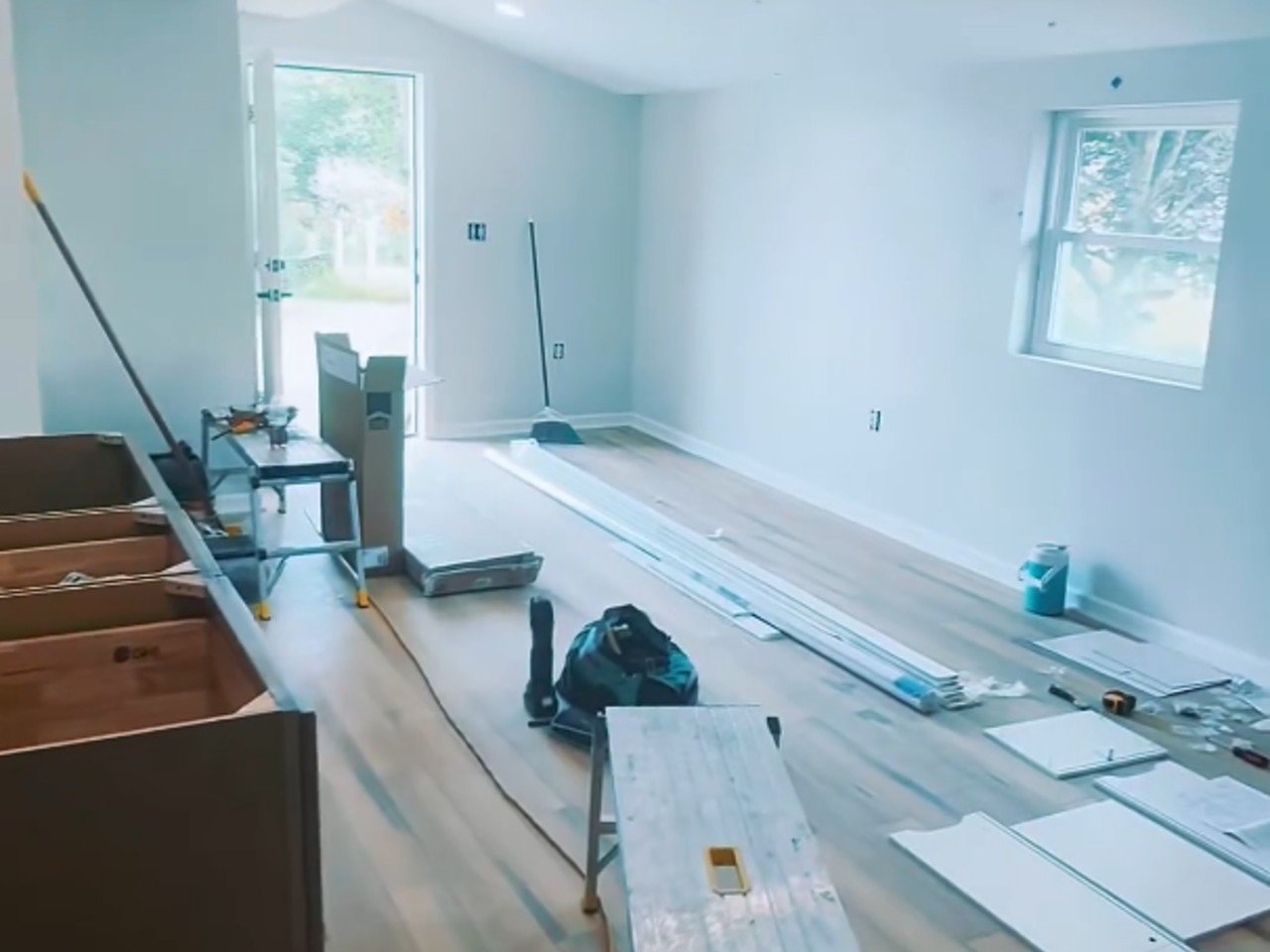A two-bay garage has been converted into a three-bedroom, one-bathroom residence with a living room, sink, and refrigerator.